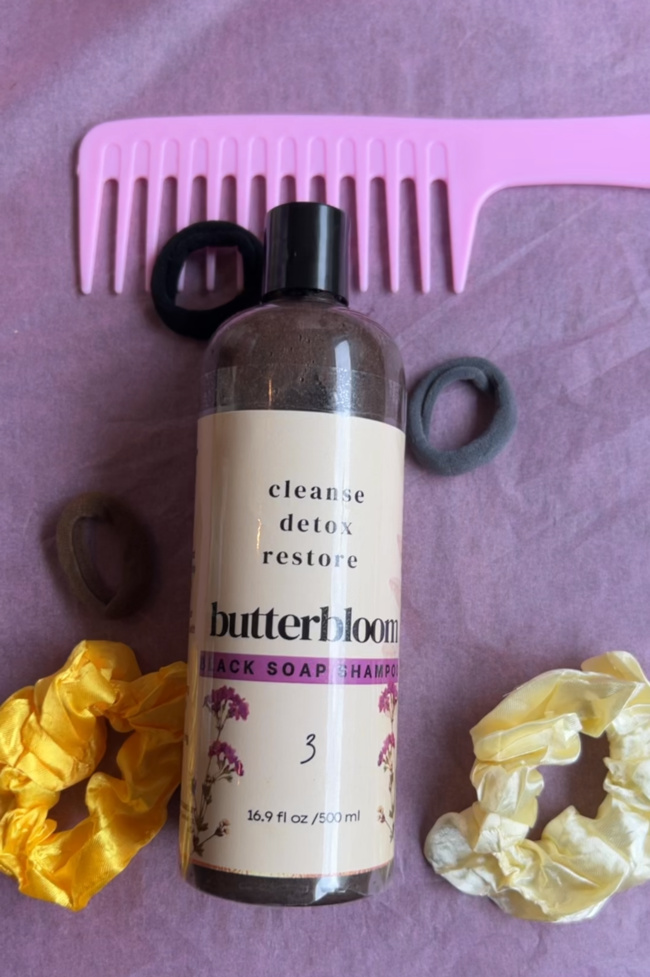 Butterbloom African black soap shampoo bottle for hair growth on a wooden surface.